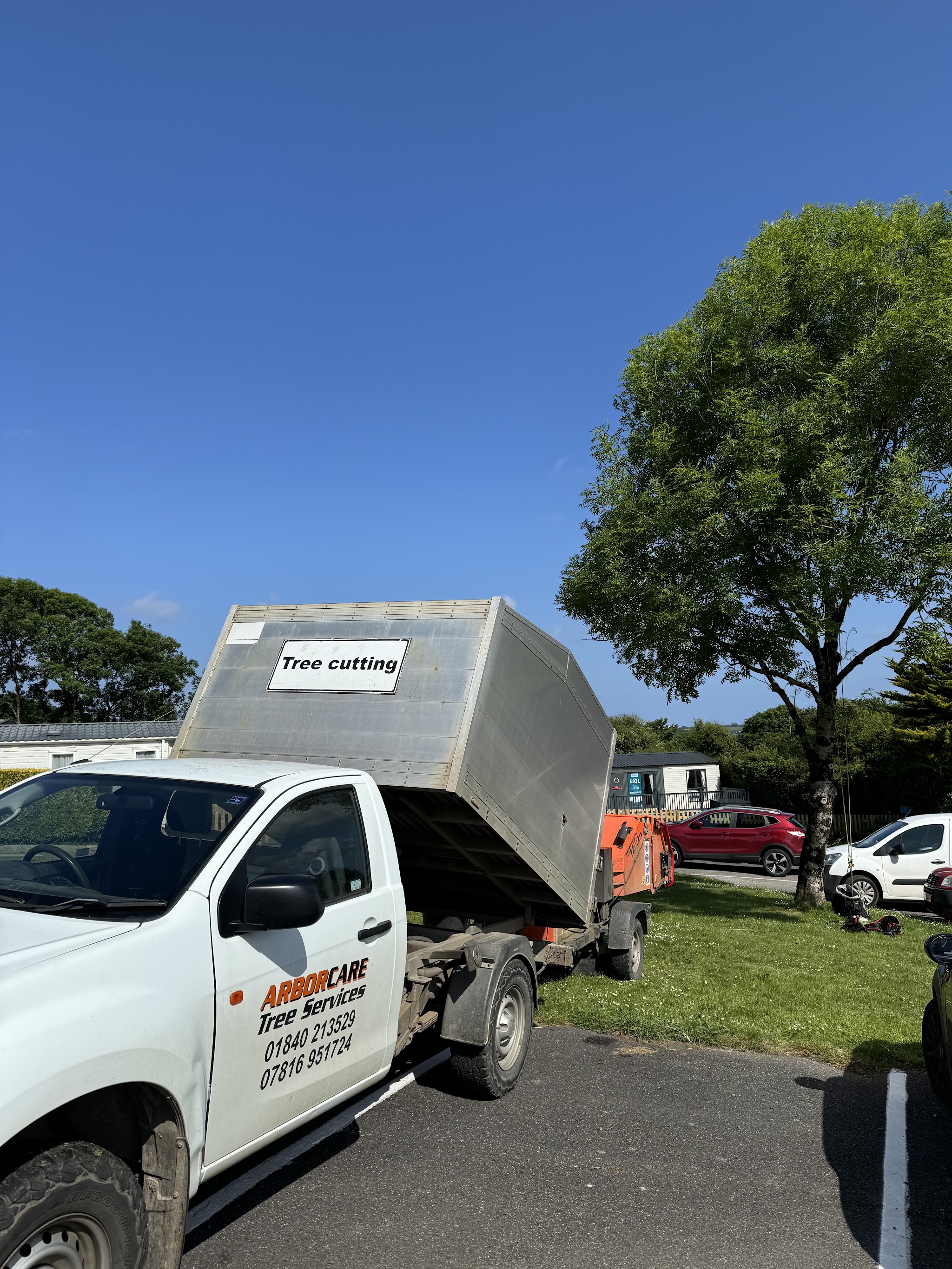 The Arborcare tipper with its Tree cutting board and phone numbers on the door, the orange chipper hitched behind